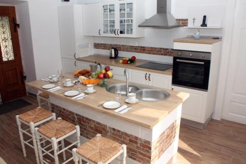 a kitchen with a counter with a sink and some chairs at Mala kuća za veliki odmor in Šilo
