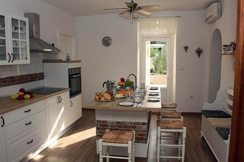 a kitchen with white cabinets and a table with fruits on it at Mala kuća za veliki odmor in Šilo