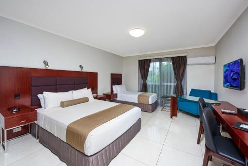 Habitación de hotel con 2 camas y escritorio en Best Western Casula Motor Inn en Liverpool