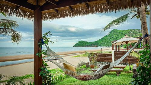 a hammock and a bench on a beach at Baan SanSuk Pranburi - Beach Front & Pool Villa in Pran Buri