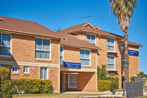 a large brick building with a palm tree at Best Western Casula Motor Inn in Liverpool
