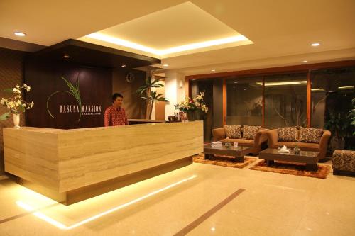 a woman standing behind a counter in a lobby at Rasuna Mansion in Jakarta