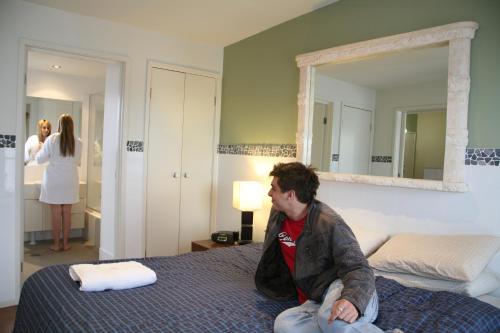 un hombre sentado en una cama en un dormitorio en Newcastle Harbourside Terraces, en Newcastle