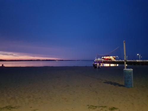a pier with a boat in the water at night at Apartament "Złoty relaks" tuż przy plaży z balkonem z widokiem na Hel i hamakami in Puck