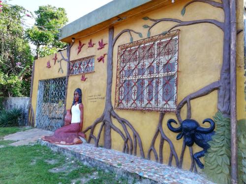 a woman standing in front of a wall with a mural at Habitat Marajó Hostel in Soure