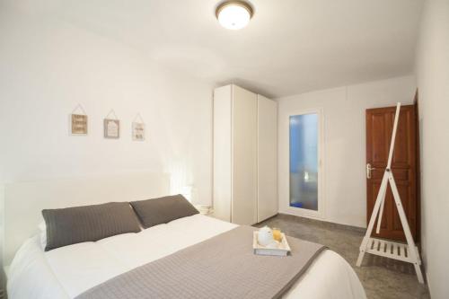 a white bedroom with a bed and a painting at Cosy Apartment Fira Barcelona in Barcelona