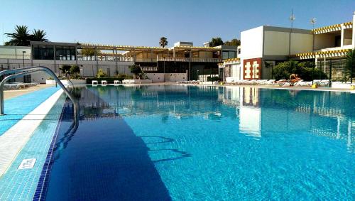 una gran piscina de agua azul frente a un edificio en Apartamento Drago, en Costa del Silencio