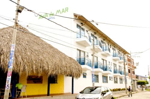 un edificio con tetto di paglia e una macchina parcheggiata di fronte di Awa De Mar Hotel a Tolú