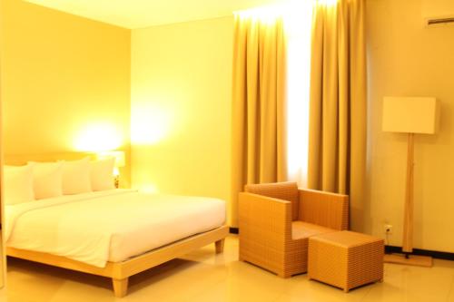 a hotel room with a bed and a chair at Hotel Santika Bengkulu in Bengkulu