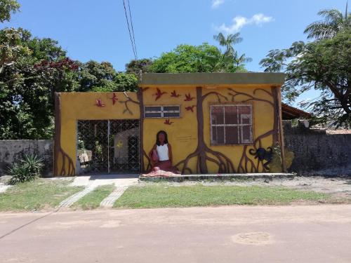 a woman sitting in the doorway of a house with graffiti at Habitat Marajó Hostel in Soure