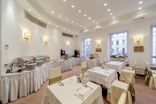 un comedor con mesas y manteles blancos en Golden Triangle Boutique Hotel, en San Petersburgo