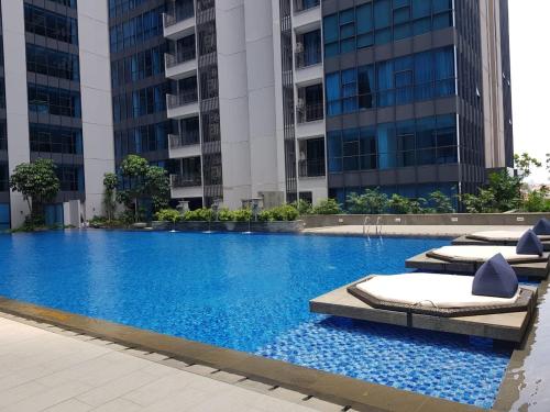 a large swimming pool with lounge chairs and buildings at Casa Grande Residence Tower Angelo in Jakarta