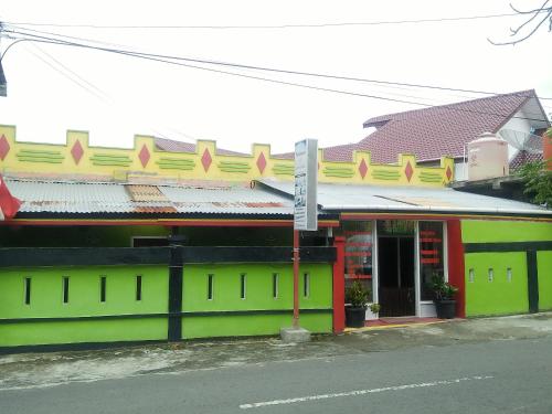 a green and yellow building on the side of a street at RedDoorz Syariah near Paradiso Beach Sabang in Sabong