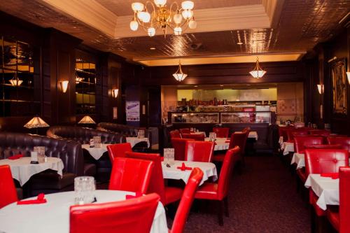un restaurante con mesas y sillas rojas en una habitación en Gilmore Hotel, Trademark Collection by Wyndham, en Ketchikan