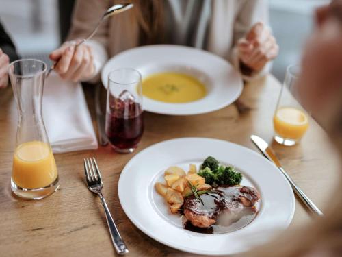 a table with two plates of food and two glasses of orange juice at Mercure Hotel Hannover Mitte in Hannover