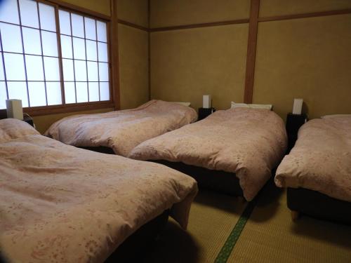 a room with four beds in a room with windows at Hunter Lodge in Myoko