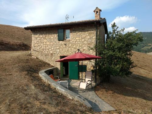 a small stone building with a red umbrella in front of it at Casetta in Sassi in Varzi