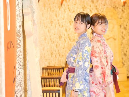 two women standing next to each other in a room at Hotel Areaone Hiroshima Wing in Higashihiroshima
