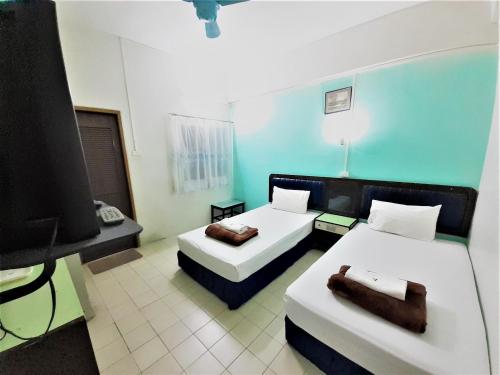 a hotel room with two beds and a television at Singapore Hotel in Hat Yai