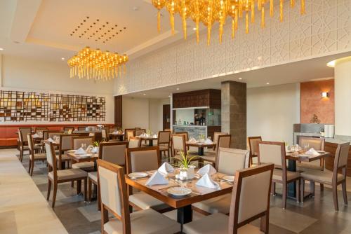 a dining room with tables and chairs and chandeliers at The Fern Sattva Resort, Dwarka in Dwarka