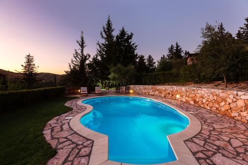 a swimming pool with a stone wall around it at Vrisali Traditional Stone Villa in Yerolákkos