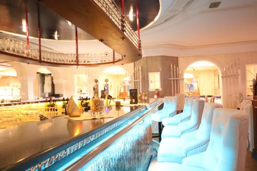 a bar with white chairs in a large room at Schlosshotel Lacknerhof in Flachau