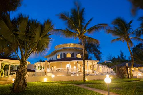 a large building with palm trees in front of it at Kobe Suite Resort in Watamu