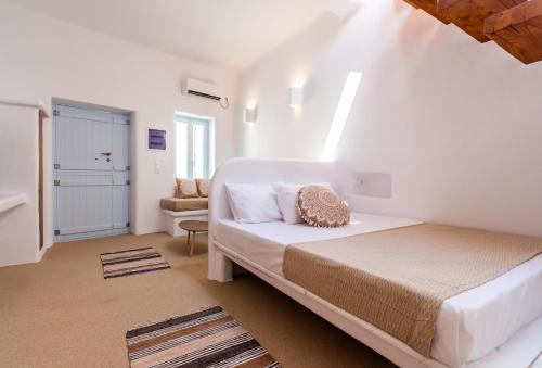 a white bedroom with a bed and a chair at Sunset Nest in Plaka Milou