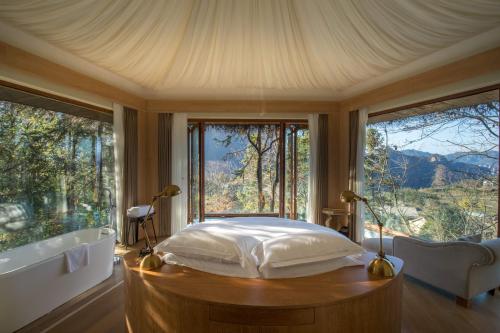 a bedroom with a bed and a tub and windows at Evergreen Retreat-walk to National Forest Park, free pick up service in Zhangjiajie