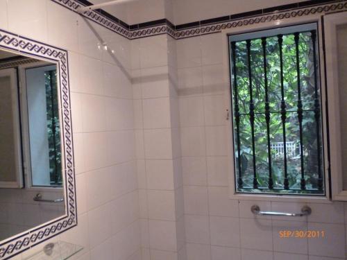 baño con espejo y ventana en Apartamentos Los Manueles, en Tolox