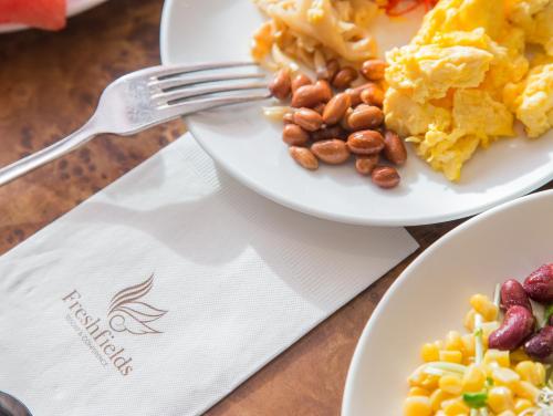 two plates of food on a table with a fork at Freshfields Hotel in Wuri