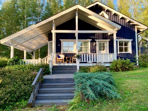 a blue house with a porch and stairs leading to it at Blueberry Villa at Saimaa Lakeside in Taipalsaari