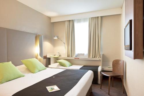 a hotel room with two beds and a window at Campanile Poitiers - Site du Futuroscope in Chasseneuil-du-Poitou