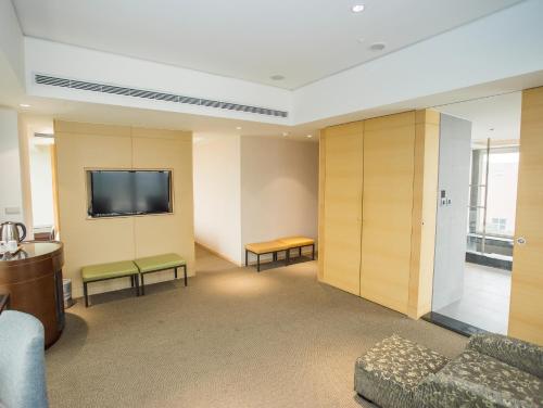 a waiting room with a couch and a flat screen tv at Freshfields Hotel in Wuri