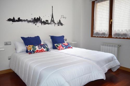 a bedroom with a large white bed with blue pillows at Piso Céntrico y Moderno in Gijón