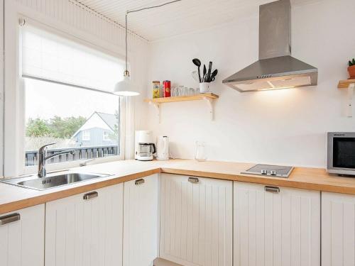 een keuken met witte kasten, een wastafel en een raam bij 4 person holiday home in Vejers Strand in Vejers Strand