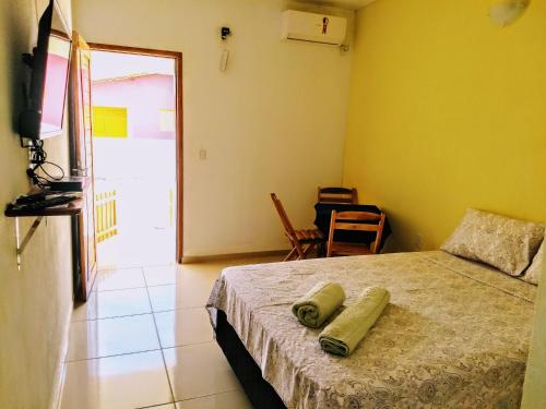 ein Schlafzimmer mit einem Bett, einem TV und einem Stuhl in der Unterkunft Pousada Ilha Bella in Galinhos