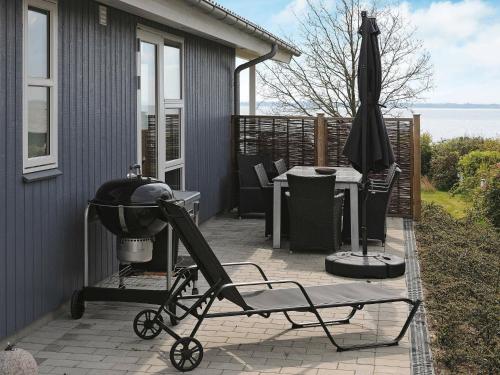 einen Kinderwagen auf einer Terrasse mit Grill und Sonnenschirm in der Unterkunft 8 person holiday home in Faaborg in Bøjden