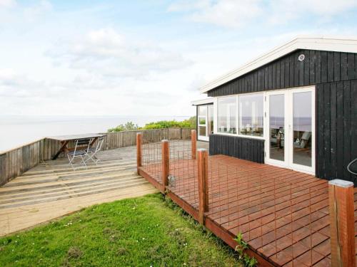 a black house with a deck and a view of the ocean at 4 person holiday home in Struer in Struer