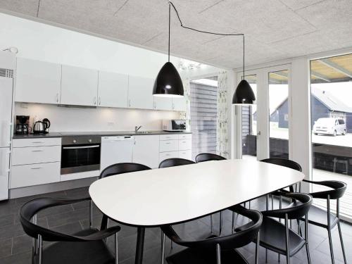 a kitchen with a white table and black chairs at 8 person holiday home in R m in Rømø Kirkeby