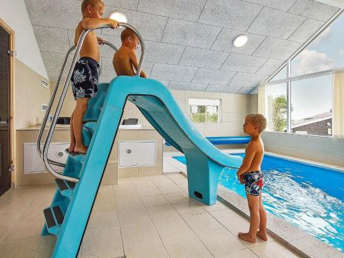 three young boys playing on a slide in a swimming pool at 14 person holiday home in Faaborg in Bøjden
