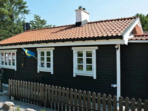 Czarny dom z czerwonym dachem i flagą w obiekcie 6 person holiday home in S LVESBORG w mieście Björkenäs