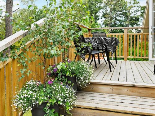 una terraza de madera con mesa, sillas y flores en 5 person holiday home in Fj llbacka, en Fjällbacka