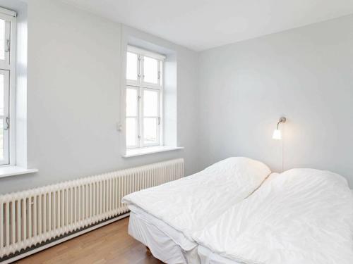 a white bedroom with a bed and two windows at 26 person holiday home in Roslev-By Traum in Åsted