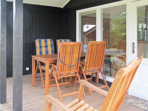 - une table et des chaises en bois sur une terrasse couverte dans l'établissement 5 person holiday home in Stege, à Stege