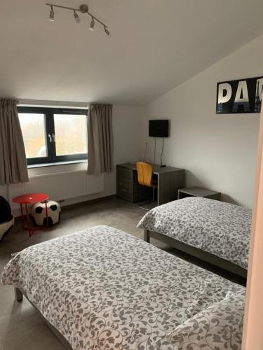 a bedroom with two beds and a desk and window at Résidence la floraison in Brussels
