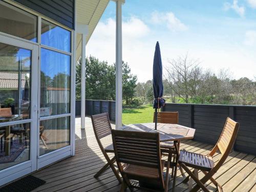 a patio with a table and chairs and an umbrella at 8 person holiday home in Ulfborg in Fjand Gårde