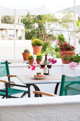 a table with glasses of wine and flowers on a patio at Notis Hotel in Samos