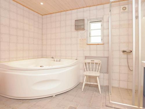 ein weißes Bad mit einer Badewanne und einem Stuhl in der Unterkunft 8 person holiday home in J gerspris in Jægerspris