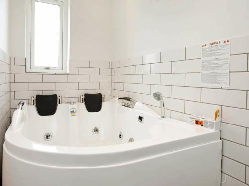 uma banheira branca numa casa de banho branca com uma janela em 8 person holiday home in R m em Rømø Kirkeby
